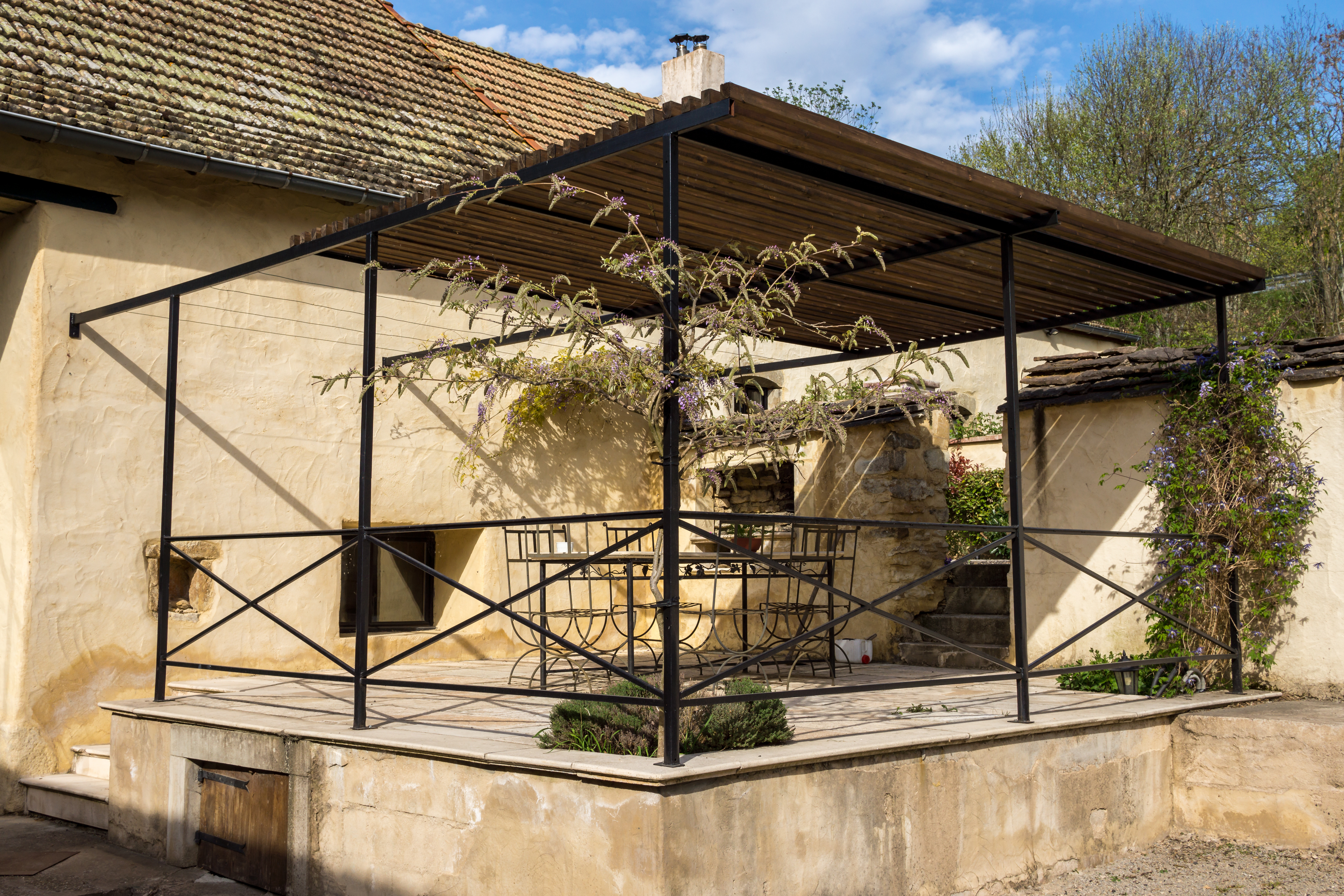 une pergola en fer forgé avec de la glycine qui pousse dessus